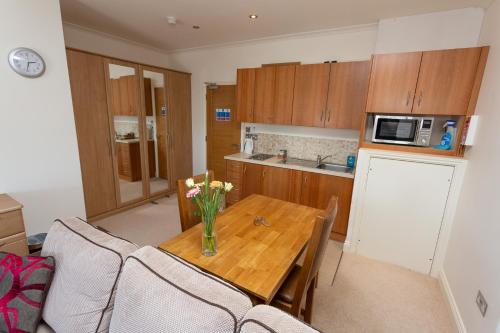 a kitchen with a wooden table with a vase of flowers on it at Porthole Suites in Saint Aubin