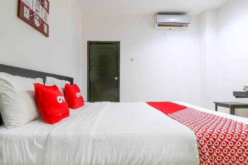 a white bed with red pillows in a bedroom at Capital O 1666 Grand Pudjawan Hotel Near Kuta Beach in Kuta