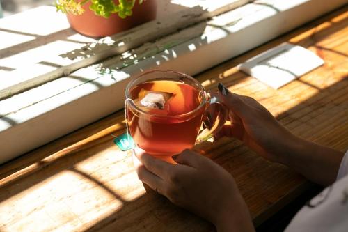 a person holding a cup of tea on a table at Hostel Like Quijote in San Carlos de Bariloche