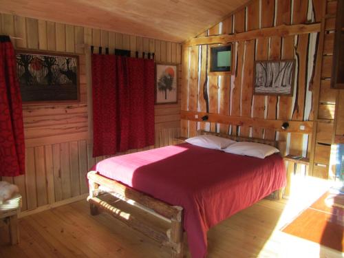um quarto com uma cama em uma sala com paredes de madeira em Cabañas Turin em Puerto Puyuhuapi