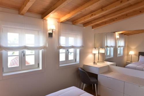 a bedroom with a bed and a desk and two windows at The Castle House in Lamego