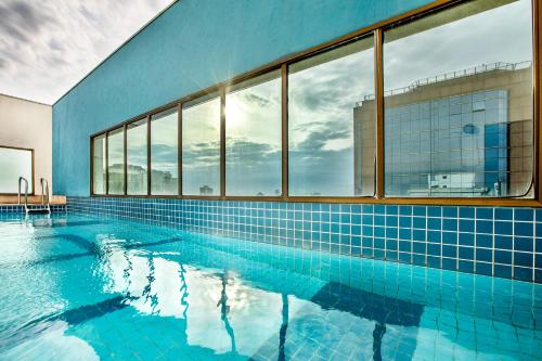 - une grande piscine dotée de carreaux bleus et de fenêtres dans l'établissement INNSiDE by Meliá São Paulo Iguatemi, à São Paulo