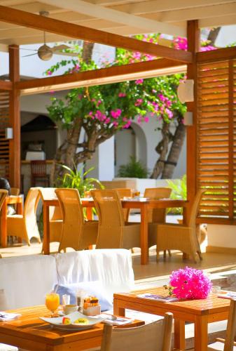 a restaurant with tables and chairs and pink flowers at Holland House Beach Hotel in Philipsburg
