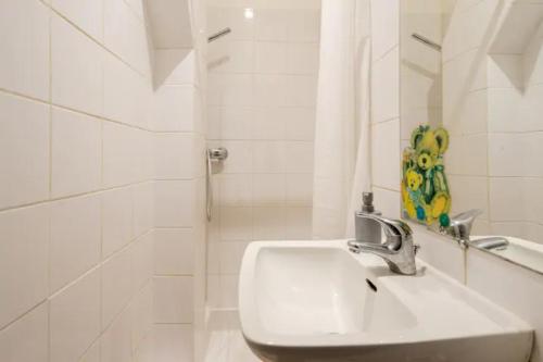 La salle de bains blanche est pourvue d'un lavabo et d'une douche. dans l'établissement PARIS Vincennes authentique -`ღ, à Vincennes