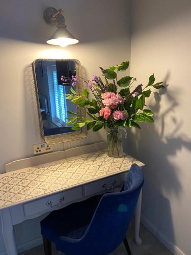a vase of flowers on a table with a mirror at Furzeleigh Mill Inn in Buckfastleigh