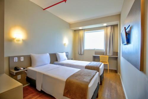 a hotel room with two beds and a desk at Transamerica FIT Sinop in Sinop