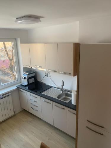 una cucina con armadi bianchi, lavandino e finestra di Apartament Izabella a Topliţa