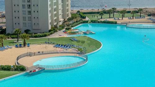 a large pool with blue water in a resort at Departamento Papudo Laguna, vista estero y mar in Papudo