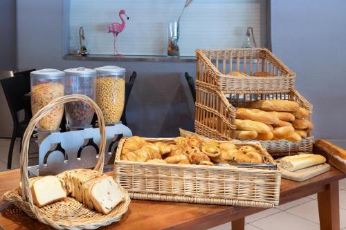 einen Tisch mit Brotkörben und Körben mit Gebäck in der Unterkunft SOWELL HOTELS L'Olivier in Arles