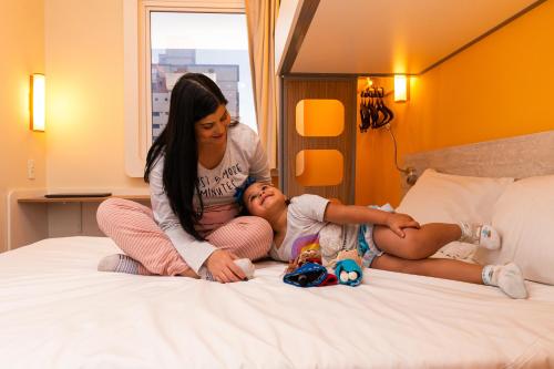 a woman and a little girl laying on a bed at ibis budget Sao Caetano in São Caetano do Sul