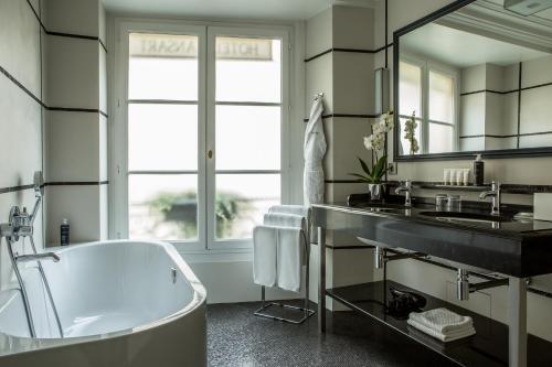 a bathroom with a tub and a sink at Hôtel Mansart - Esprit de France in Paris