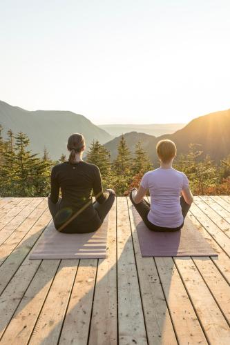 two women sitting on a wooden deck looking at the mountains at Auberge de Montagne des Chic-Chocs Mountain Lodge - Sepaq in Sainte-Anne-des-Monts