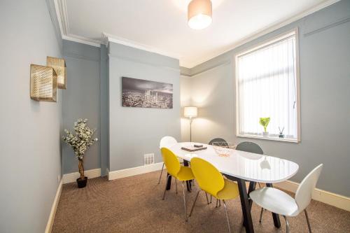a dining room with a white table and yellow chairs at Large Contractor & Worker House - Free Parking in Liverpool