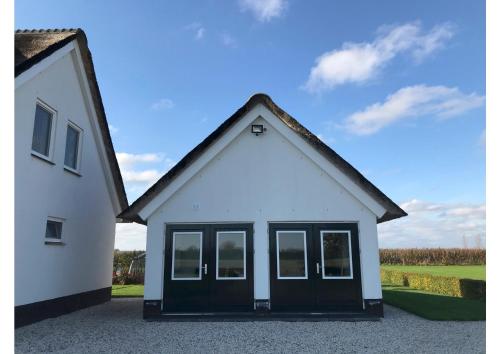a white house with black doors and a field at B&B De Spiegel - Genieten van rust en ruimte in Cothen