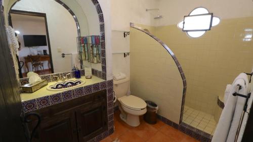 a bathroom with a toilet and a sink and a mirror at Casa Mia Suites in San Miguel de Allende