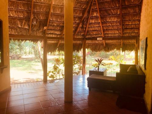 a room with a thatched roof with a couch in the middle at La Palapa Hut Nature Hostel in Puerto Jiménez