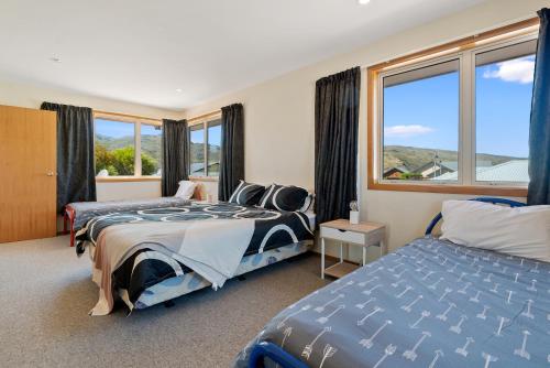 a bedroom with two beds and a large window at Southern Belle - Cromwell Holiday Home in Cromwell