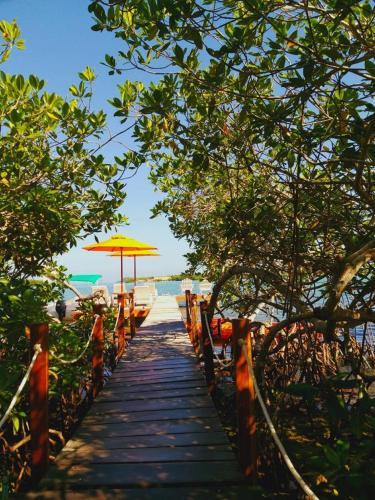 a wooden pathway with an umbrella on the beach at Hotel Playa Scondida Barú in Baru