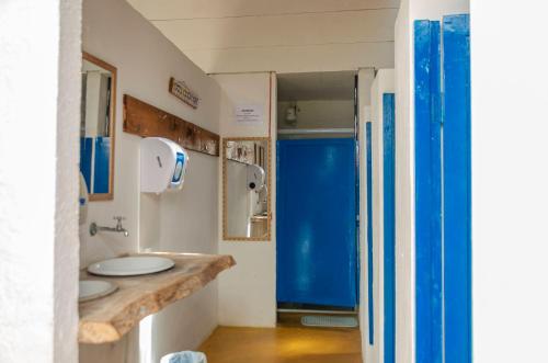 uma casa de banho com dois lavatórios e uma porta azul em Clan.Destino Hostel em Ilhabela