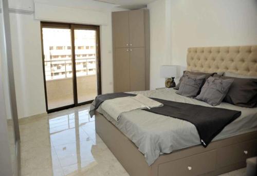 a bedroom with a large bed with a large window at Amazing one Bedroom Apartment in Amman Elwebdah 2 in Amman