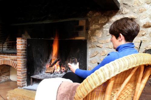 a man sitting in front of a fireplace holding a wine glass at Complejo Rural Turimaestrat in Sant Mateu