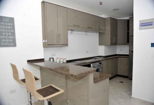 a kitchen with white cabinets and a counter and chairs at Amazing one Bedroom Apartment in Amman Elwebdah 4 in Amman