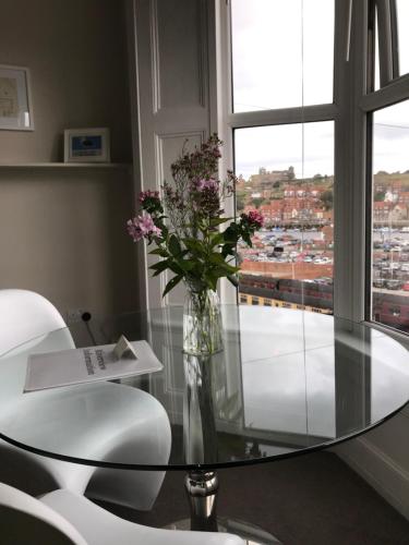 a glass table with a vase of flowers on it at Riverview Apartment with Private Parking in Whitby