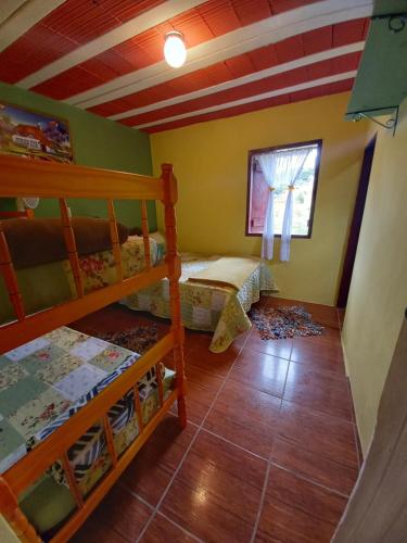 a bedroom with two bunk beds and a window at Chalés Encantos de Cunha Azul in Cunha