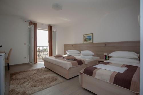 a bedroom with two beds and a balcony at Apartments Bota in Drvenik