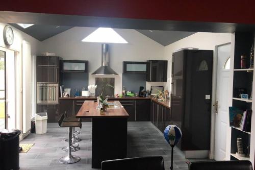 Il dispose d'une grande cuisine avec une table et un réfrigérateur. dans l'établissement Villa « Beauséjour » Urville-Nacqueville de 180 M2, à Urville-Nacqueville