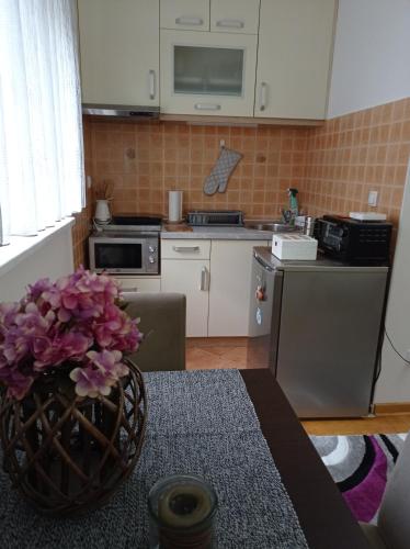 a kitchen with a vase of flowers on a table at Apartman Harmonija Vrnjačka Banja in Vrnjačka Banja
