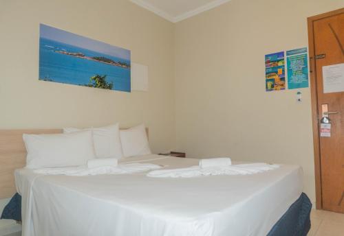 a large white bed in a white room with a picture at UPG Hotel in Ubatuba