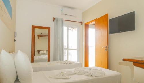 a bedroom with two white beds and a mirror at UPG Hotel in Ubatuba