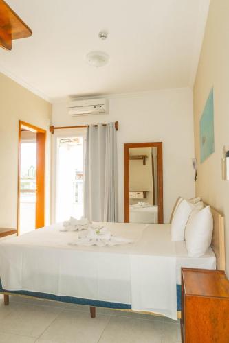 a large white bed in a room with a window at UPG Hotel in Ubatuba