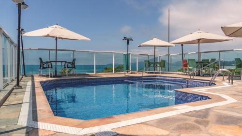 a swimming pool with tables and umbrellas on a building at UPG Hotel in Ubatuba
