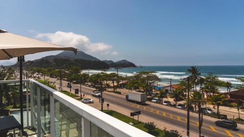 a balcony with a view of a road and the ocean at UPG Hotel in Ubatuba