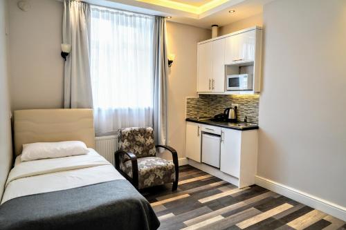 ロンドンにあるブティック アパートメンツのベッド1台、椅子、キッチンが備わる小さな客室です。