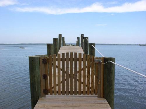 a wooden dock with a gate on a body of water at Birchwood inn in Chincoteague