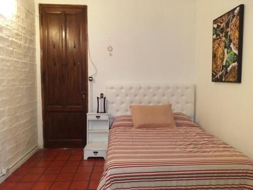 1 dormitorio con 1 cama y puerta de madera en Gachishouse en Buenos Aires