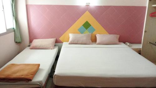 two beds in a room with a colorful wall at Center Mansion at Hatyai in Hat Yai