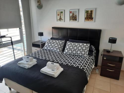 a bedroom with a black bed with towels on it at Departamento en San Juan, Argentina in San Juan