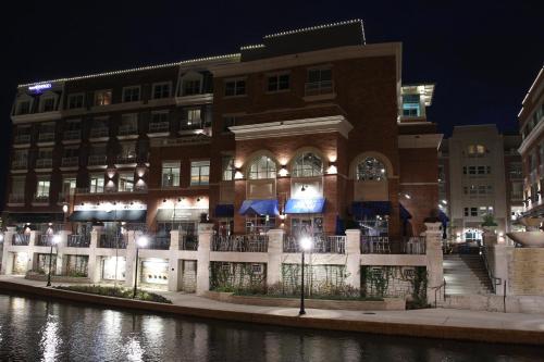 a large building next to a river at night at Hotel Indigo Naperville Riverwalk by IHG in Naperville