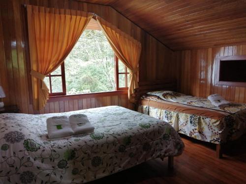 a bedroom with two beds and a window at Illariy Tampu Ecoalbergue Oxapampa in Oxapampa