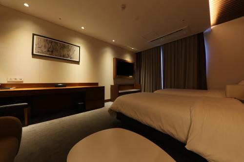 a hotel room with a bed and a desk at Sejong City Osong Hotel in Cheongju