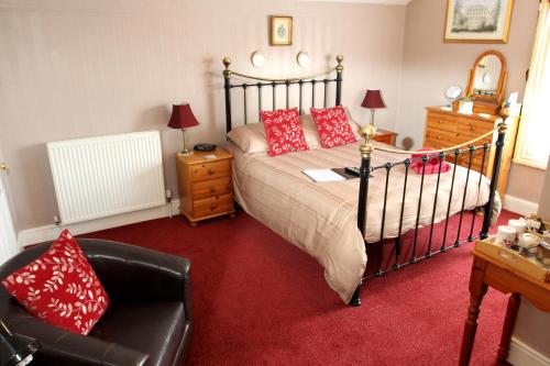 a bedroom with a bed with red pillows and a chair at Camellia Lodge Guest House in Weston-super-Mare