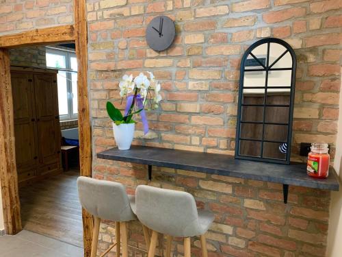 a brick wall with a counter with two chairs and a clock at Magiczne Mieszkanko in Piła