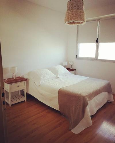 una camera con un letto bianco e due tavoli di Luz de Madryn a Puerto Madryn