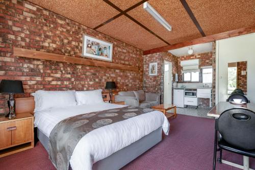 a bedroom with a bed and a brick wall at Kerang Valley Resort in Kerang