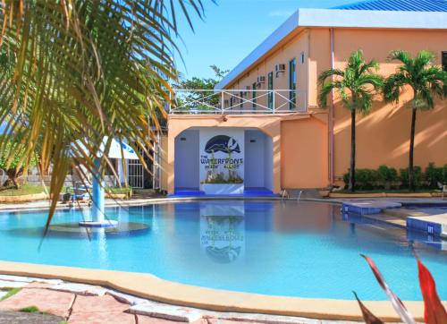 a large swimming pool with palm trees in front of a building at The Waterfront Beach Resort in Morong