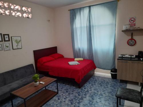 1 dormitorio con cama roja y sofá en Alborada minisuites en Guayaquil